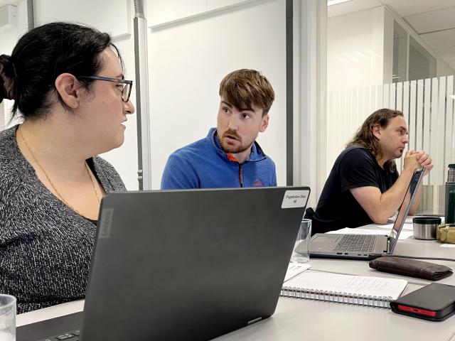 En kvinne og en mann sitter i et klasserom og diskuterer foran en pc-skjerm. 