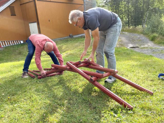 To menn jobber sammen om å bygge en bro av stokker